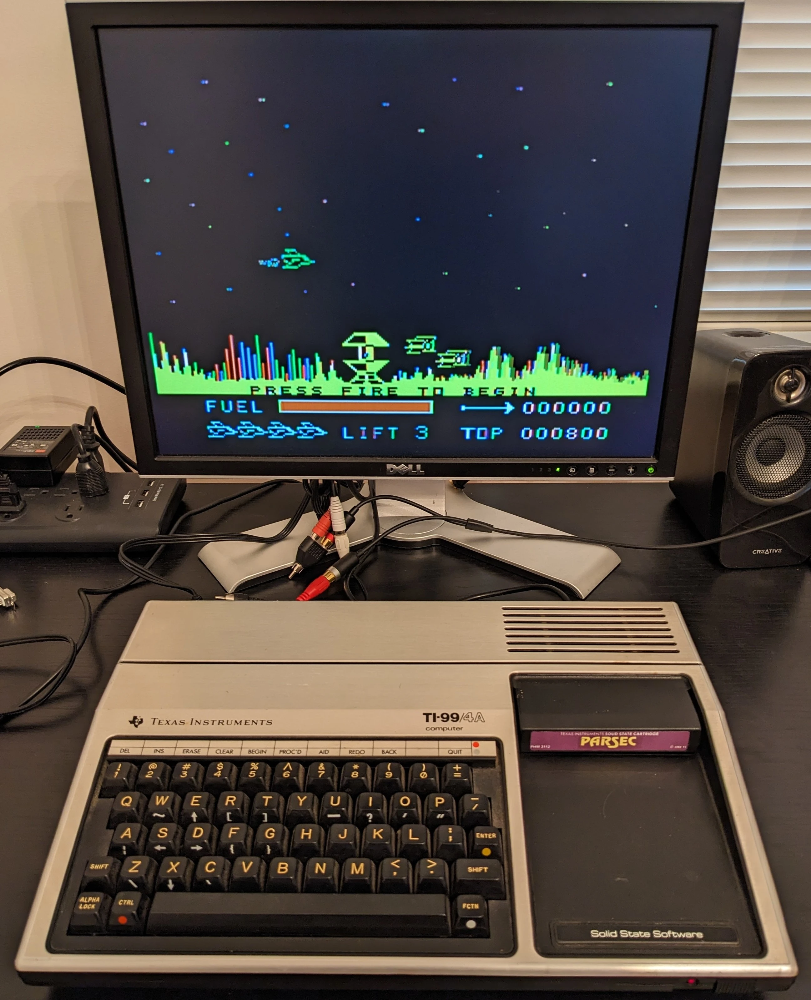 A TI-99/4A connected to a Dell LCD monitor on composite, playing Parsec from a cartridge.