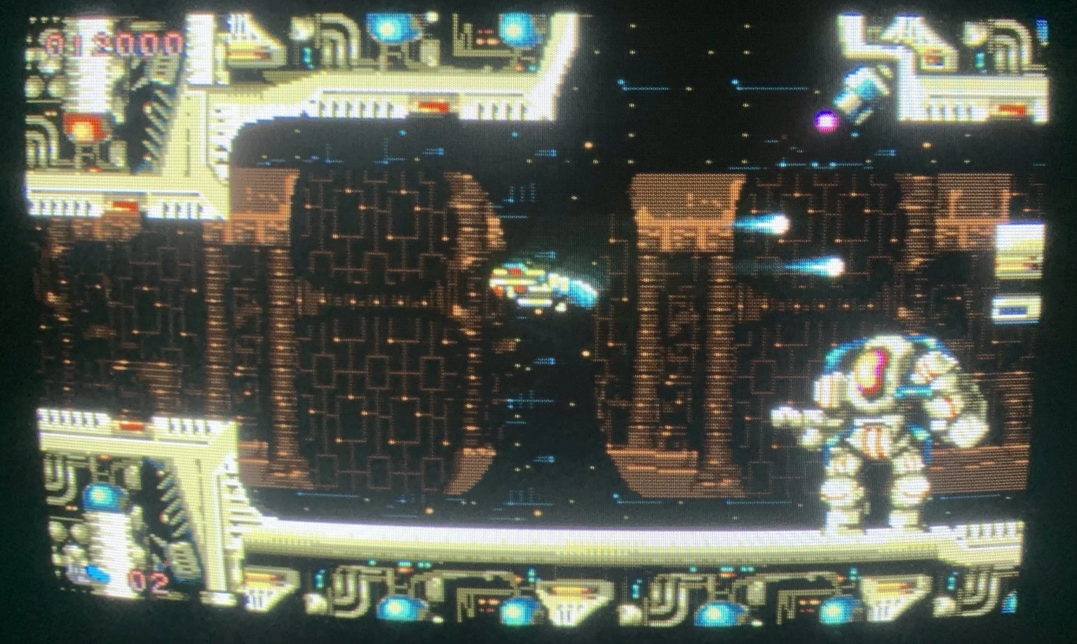 A pixelated CRT screen showing a kind of scifi space ship interior. A mecha robot at the right edge seems to be the opponent. A small spacefighter is in the center of the screen. 